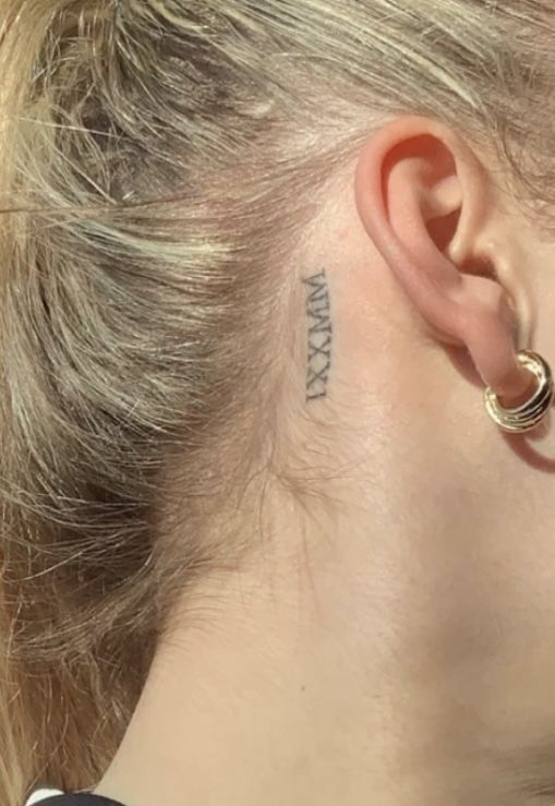 Hình xăm số La Mã sau tai, phong cách blackwork, chi tiết nhỏ, ảnh chất lượng HD.