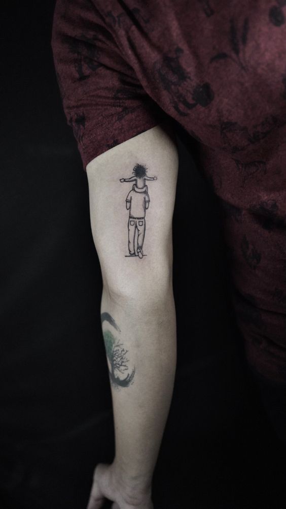 Tattoo đơn giản nhưng sâu sắc về tình cha con Hình xăm mini phong cách blackwork trên bắp tay, hình người đứng với cây gậy, ảnh độ phân giải cao.