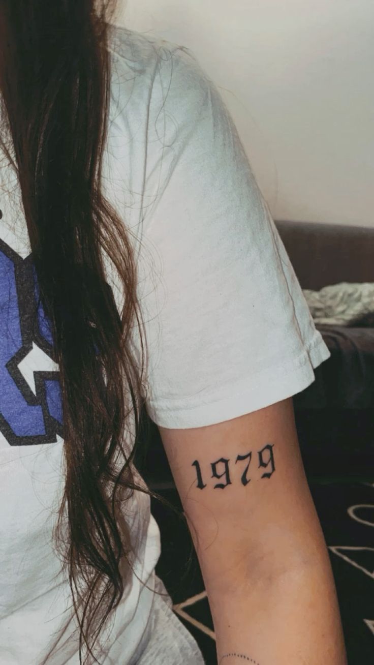 Hình xăm chữ số "1979" trên cánh tay, phong cách cổ điển, chi tiết rõ nét, ảnh HD.