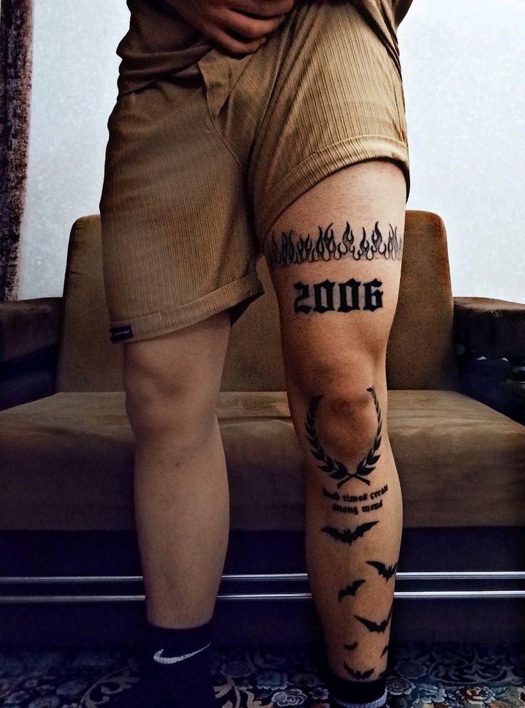 Hình xăm chữ và hình lửa trên đùi, phong cách blackwork, chi tiết rõ nét, độ phân giải HD.