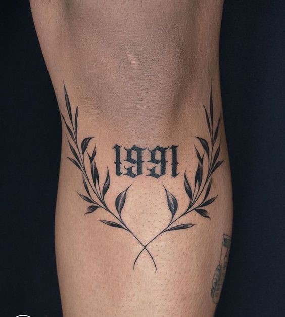 Hình xăm số "1991" và lá nguyệt quế, vị trí bắp tay, phong cách blackwork, độ chi tiết cao, ảnh HD.