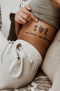 Hình xăm chữ và hoa phong cách blackwork trên eo, ảnh chi tiết HD.