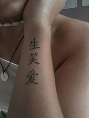 thể hiện quan niệm sống lạc quan Hình xăm chữ trên cánh tay, phong cách tối giản, độ phân giải HD, chữ đen rõ nét.