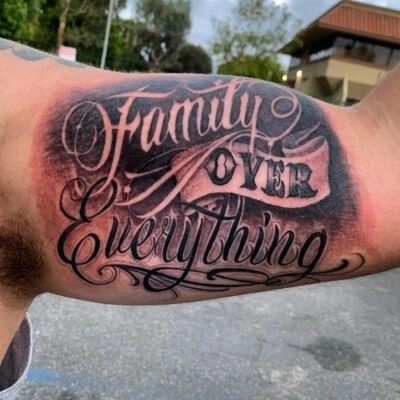 Hình xăm chữ "Family Over Everything" trên bắp tay, phong cách blackwork, ảnh độ phân giải HD.