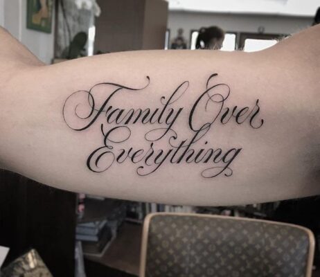 Hình xăm chữ "Family Over Everything" trên bắp tay, phong cách cổ điển, ảnh HD chi tiết.