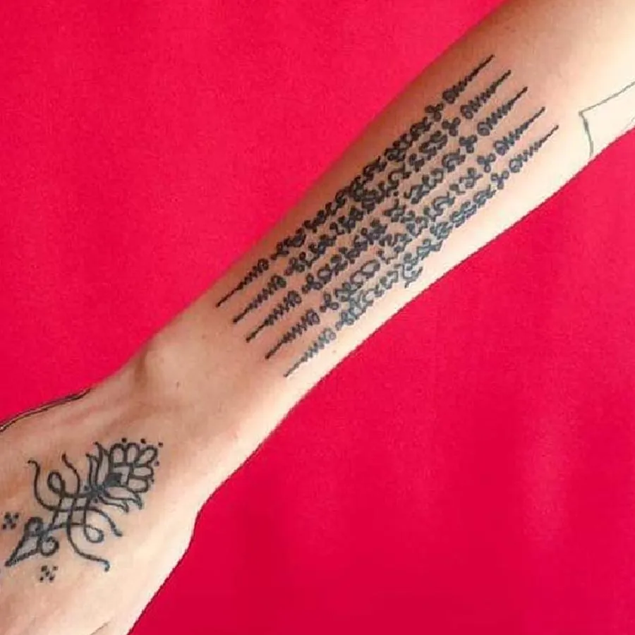 Hình xăm chữ cổ tay, phong cách blackwork, chi tiết rõ nét, nền đỏ, độ phân giải HD.