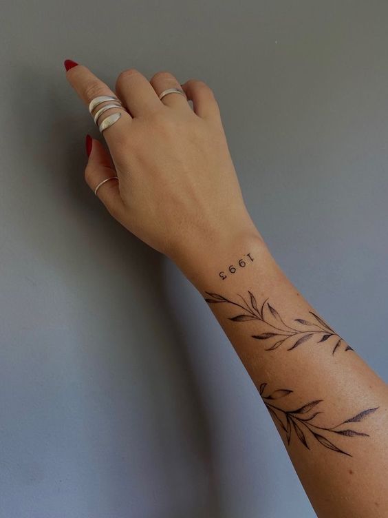 Hình xăm lá cành tối giản trên cẳng tay, phong cách blackwork, độ phân giải HD.