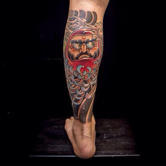 Xăm kín bắp chân hình Daruma với hoa mẫu đơn xanh đầy sáng tạo Hình xăm chân phong cách Nhật Bản, họa tiết mặt người, nhiều màu sắc, độ chi tiết cao, độ phân giải HD.