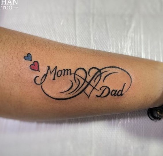 Hình xăm chữ "Mom Dad" với trái tim, phong cách chữ nghệ thuật trên tay, chi tiết rõ nét, ảnh HD.