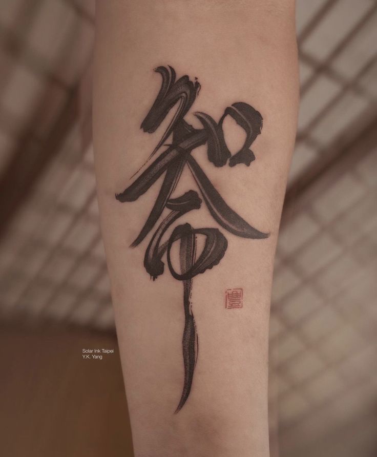 Hình xăm chữ phong cách thư pháp trên cánh tay, tông màu đen, chi tiết rõ nét, ảnh độ phân giải cao.
