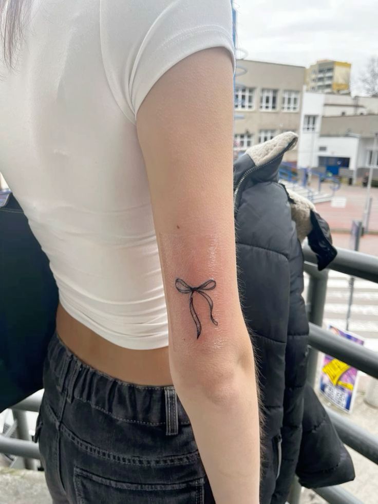 xăm nơ màu đen đơn giản Hình xăm nơ đơn giản trên cánh tay, phong cách blackwork, chất lượng HD.