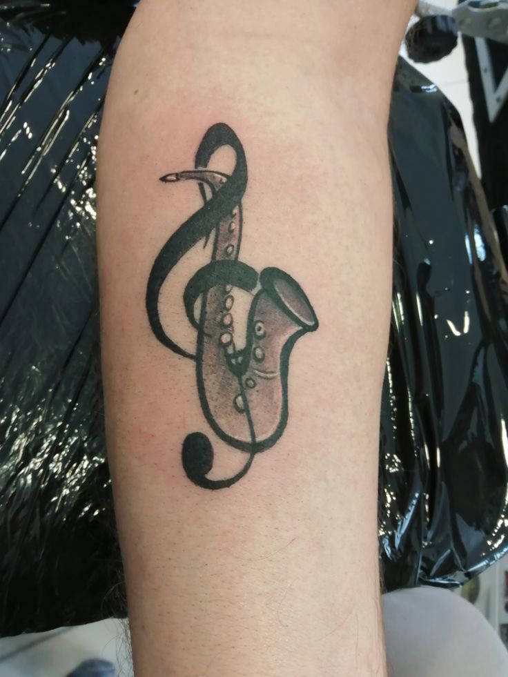 Hình xăm kèn saxophone trên cánh tay, phong cách blackwork, chi tiết rõ nét, ảnh HD.