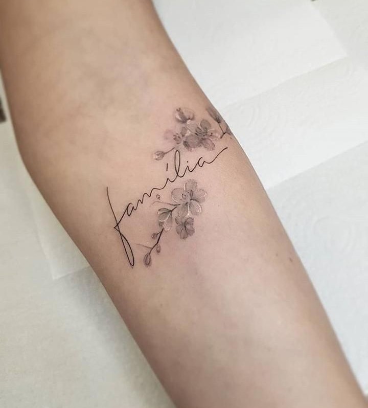 Ý nghĩa sâu sắc của hoa về gia đình Hình xăm chữ "família" và hoa tinh tế trên tay, phong cách blackwork, ảnh HD.