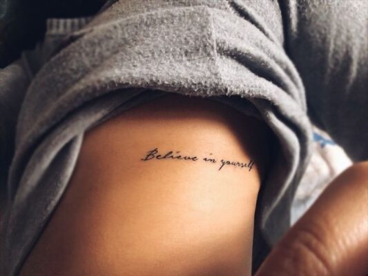 ý tưởng tattoo chữ believe in yourself ở mạn sườn Hình xăm chữ "Believe in yourself" trên xương sườn, phong cách tối giản, độ phân giải HD.