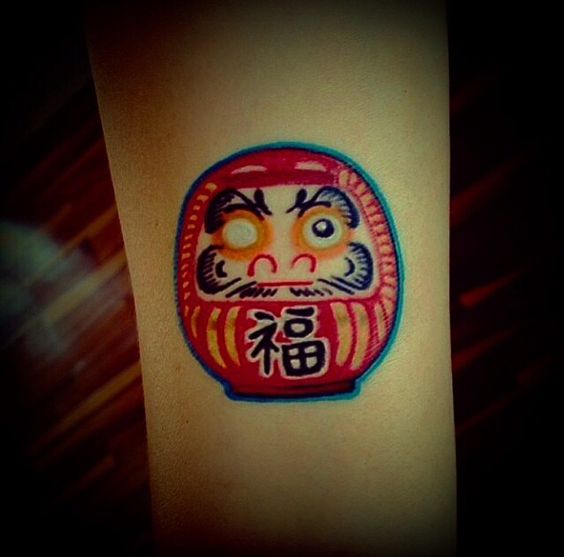 ý tưởng xăm daruma mặt tròn mang lại may mắn Hình xăm búp bê Daruma trên tay, phong cách màu sắc, chi tiết rõ nét, độ phân giải HD.