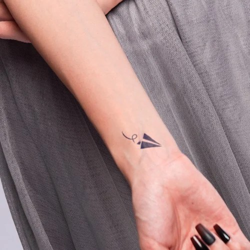 Hình xăm máy bay giấy mini trên cổ tay, phong cách blackwork, ảnh HD chi tiết rõ ràng.