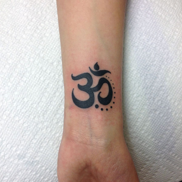 Hình xăm ký tự Om trên cổ tay, phong cách blackwork, chi tiết rõ nét, ảnh HD.